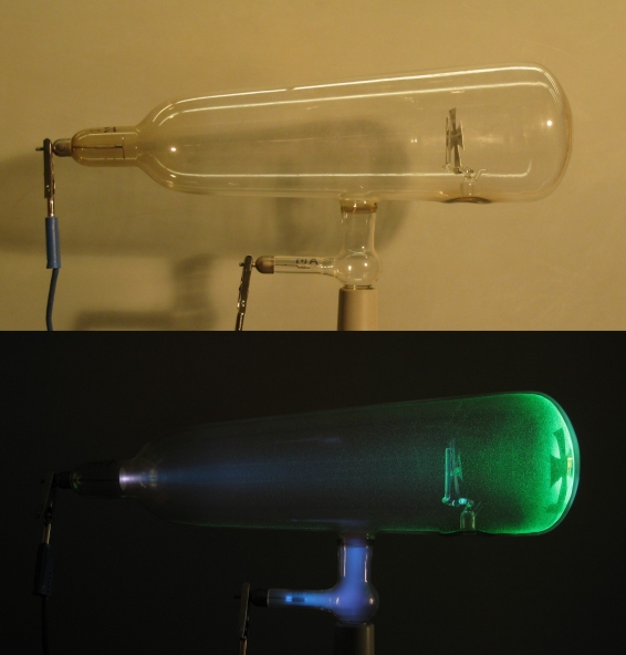 Duas fotos do Tubo de Crookes. A foto inferior mostra o tubo ativado, com a luminosidade causada pelo feixe de elétrons, chamado de raios catódicos